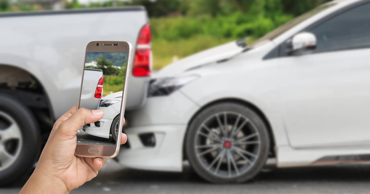 Man using his smartphone to take a photo of a rear-end collision between a pickup truck and a sedan | Colombo Law