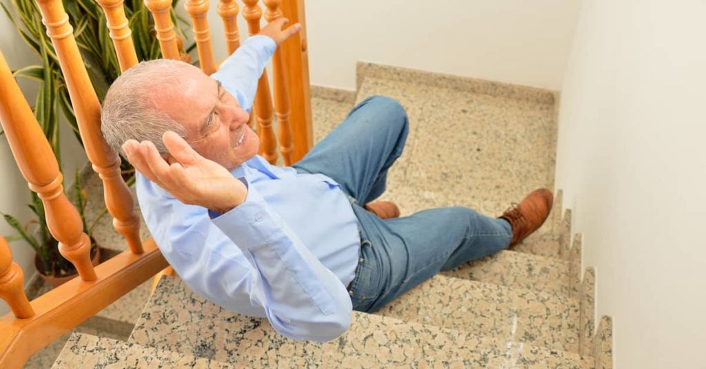 elderly man falling down stairs with his hands out trying to grab railing