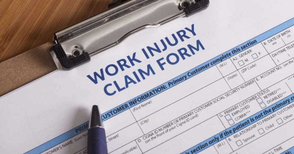 Work Injury Claim Form and pen resting on a clipboard