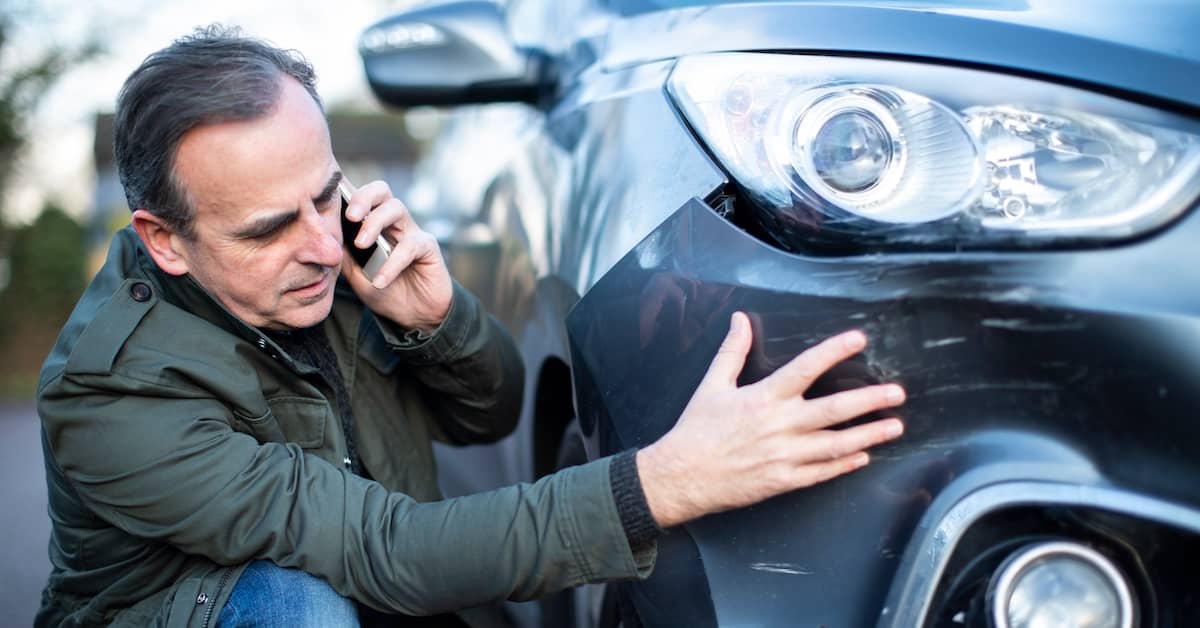 middle-aged man calling his insurance company after a car accident