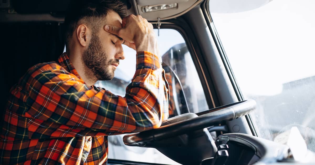 tired, overworked truck driver in the cab of his rig