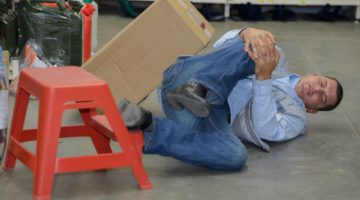 injured worker holding his leg after falling off a step stool