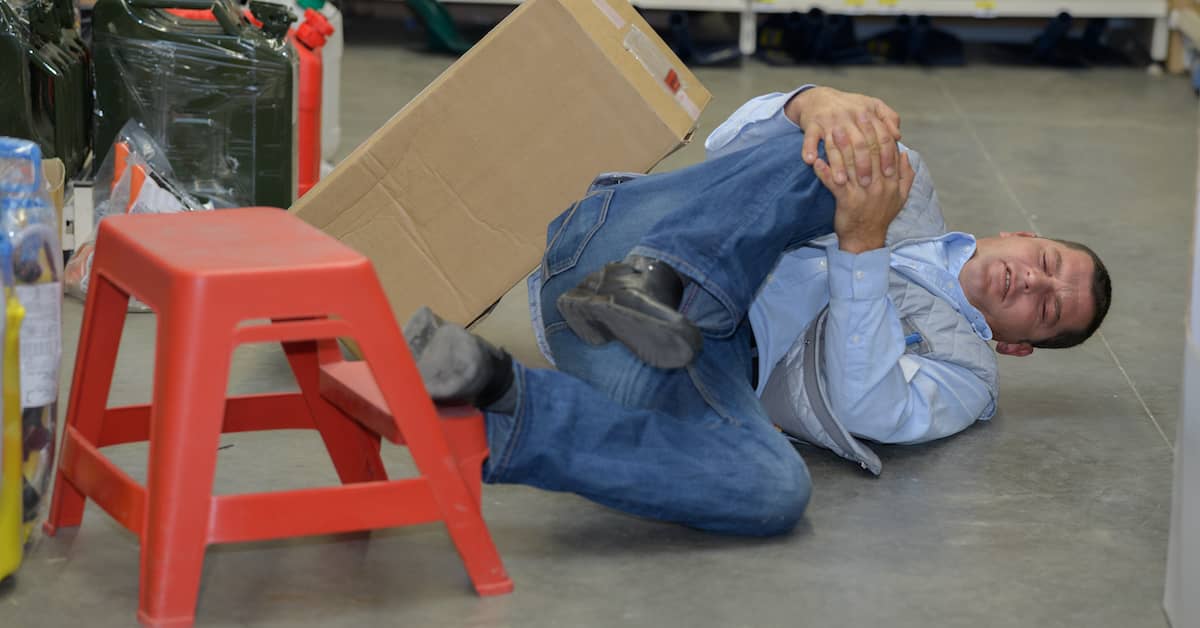 injured worker holding his leg after falling off a step stool