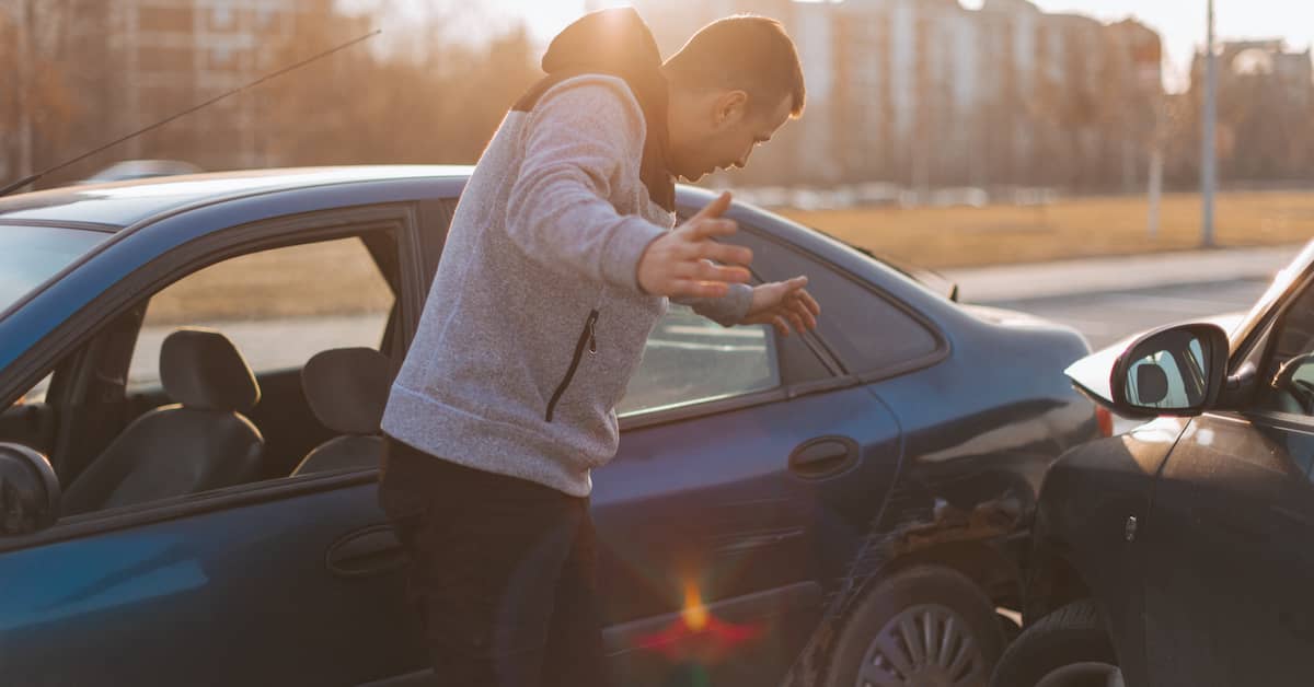 Driver gesturing in disbelief at the damage in a car accident | Colombo Law