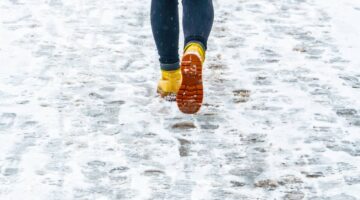 Woman in boots walking on snowy sidewalk | Colombo Law