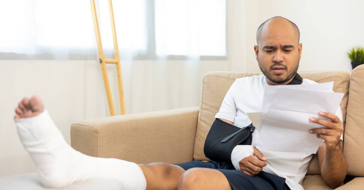 Injured man on couch reading medical bill in disbelief | Colombo Law