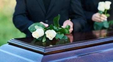 Mourners laying flowers on a casket | Colombo Law