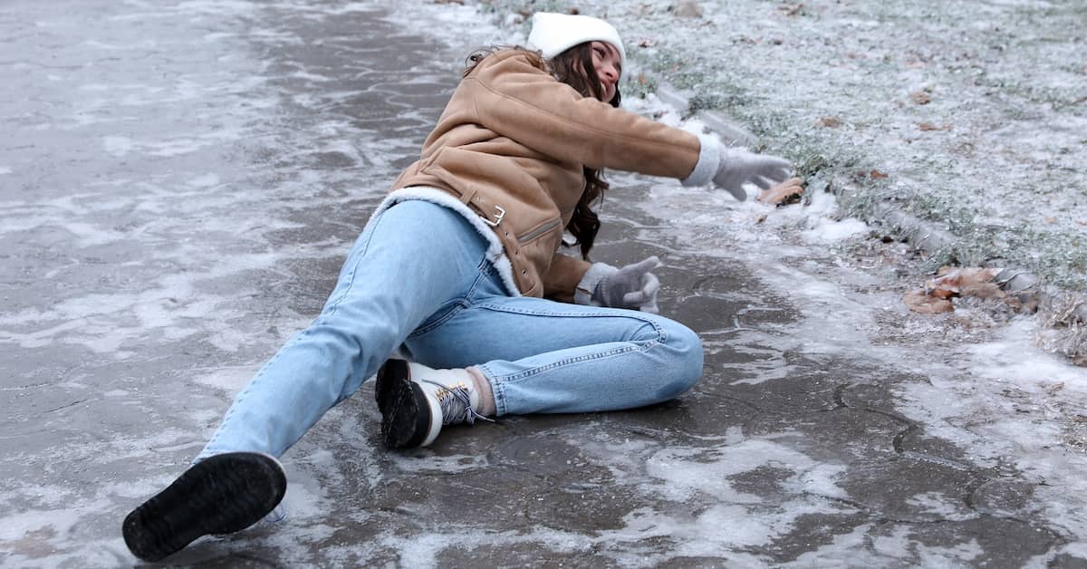 Woman lying injured on the ground after slipping on an icy sidewalk | Colombo Law