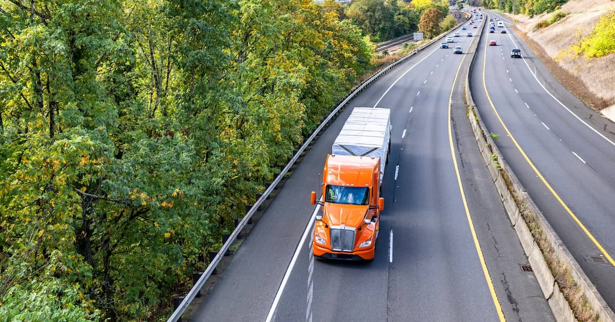 Tractor-trailer driving on the highway through a wooded area | Colombo Law