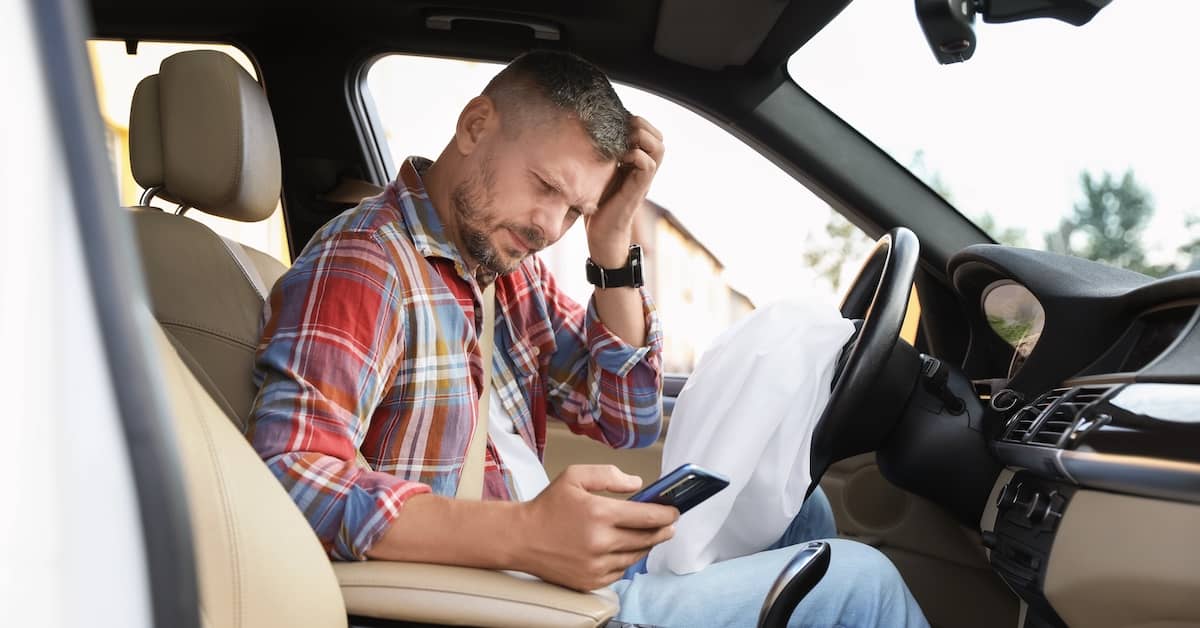 Injured man looking at his phone after being in a car accident | Colombo Law