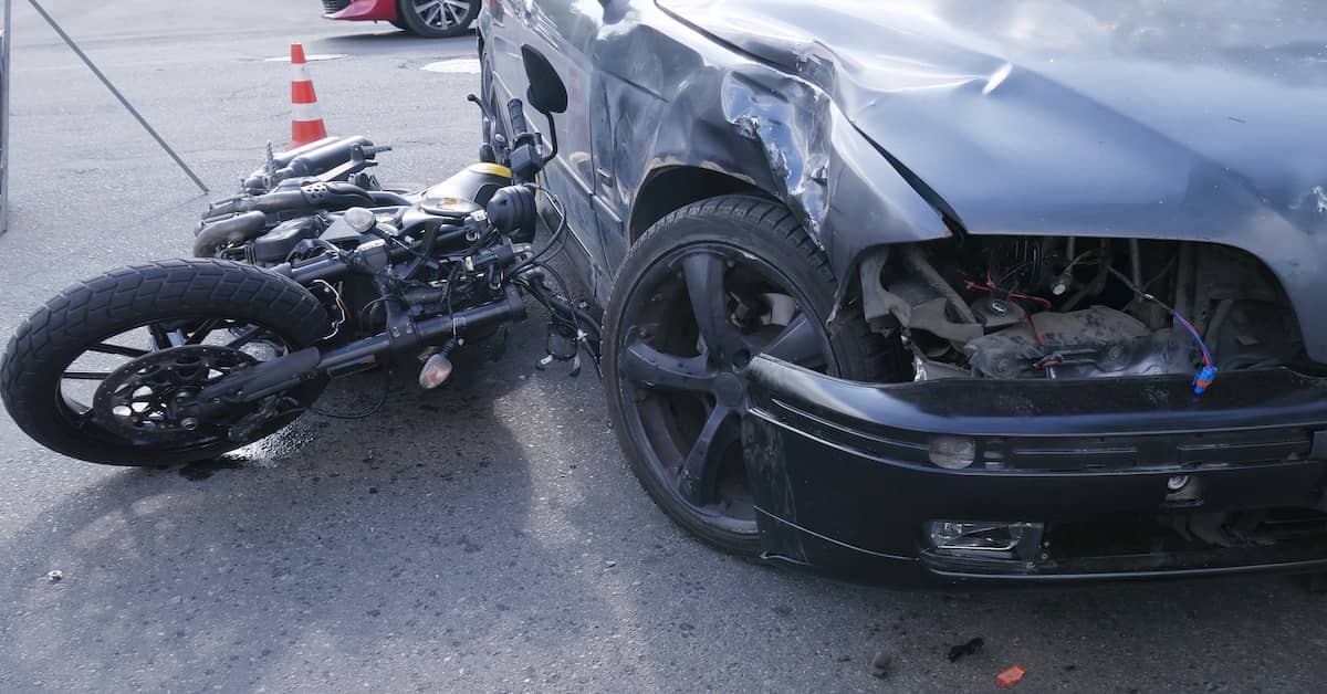 Damaged motorcycle underneath a car that hit it | Colombo Law