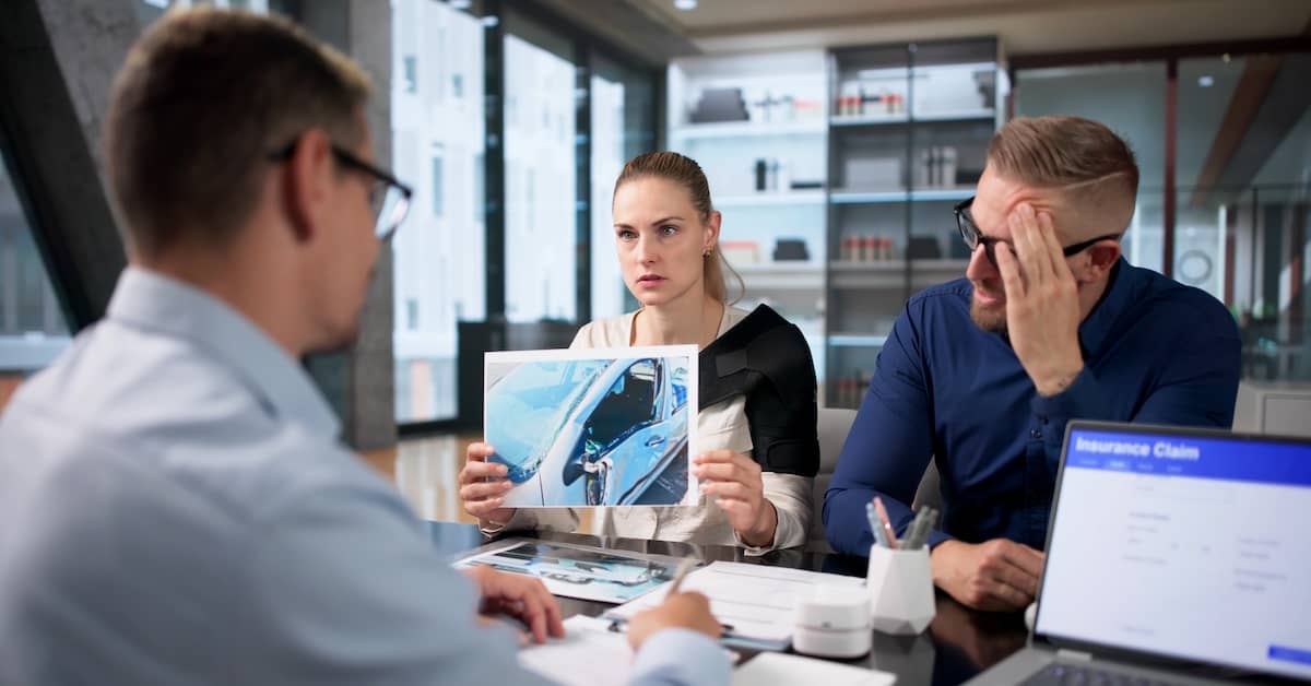 Upset man and woman discussing car accident settlement with an insurance adjuster | Colombo Law