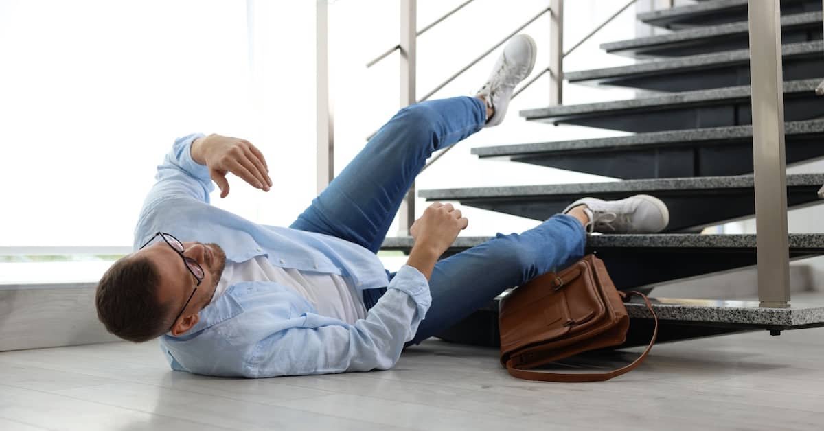Young man lying on his back injured after slipping and falling down the stairs in a business lobby | Colombo Law